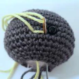 Lime yarn embroidered over two stitches as blush beside the eye of a crochet bat