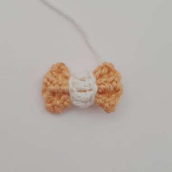 Finished crochet bow tie in apricot with a white knot in the center