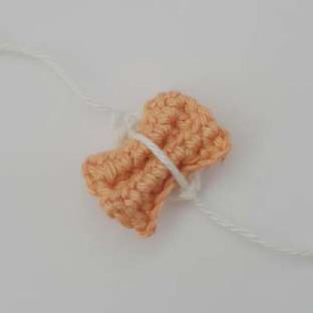 Apricot crochet bow pinched inside a white loop