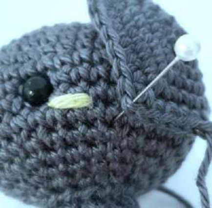 Pin holding the front corner of a crochet bat ear just behind the lime blush
