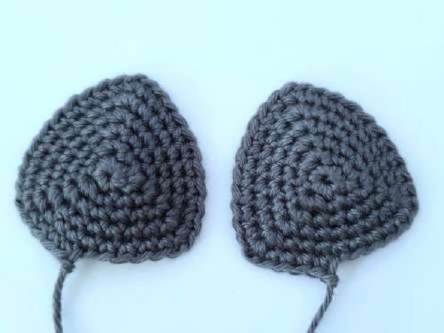 Two flat crochet bat ears in charcoal cotton, rounded triangles with long yarn tails