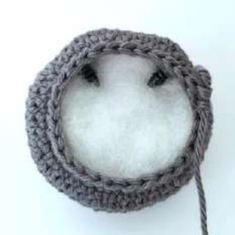 Inside of a crochet bat head with stuffing tucked above the safety eyes