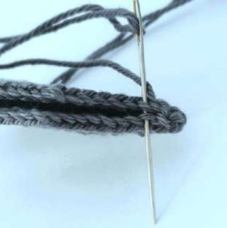 Folded crochet wing being sewn closed through the back loops with a tapestry needle