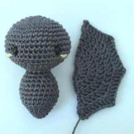 Finished crochet bat wing next to the joined head and body, almost the same height