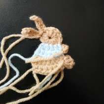 Crochet bunny with a small beige arm over the sweater