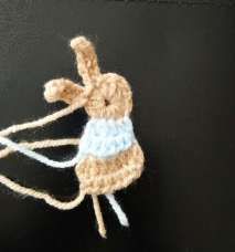 Crochet bunny with a pale blue sweater and the beige rows below it