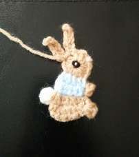 Finished crochet bunny applique with a black eye and a white tail