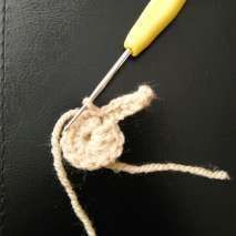 Beige crochet ring with the first bunny ear starting, on a dark background