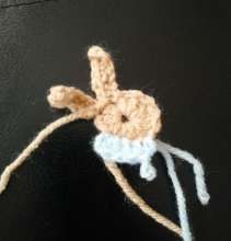 Crochet bunny head with the first rows of the pale blue sweater