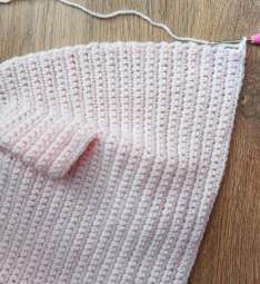 Pink crochet cardigan front with the buttonhole band started