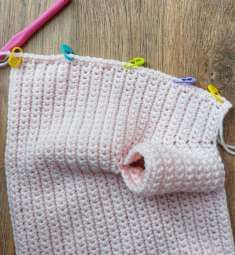 Colored stitch markers along the front edge of the pink cardigan
