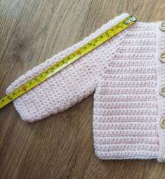 Measuring tape laid along the sleeve of the pink crochet cardigan
