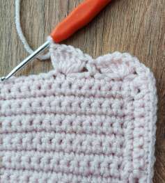 First crochet shell at the corner of the pink cardigan, next to the band