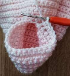 Crochet hook joining yarn at the underarm of the pink cardigan to start a sleeve