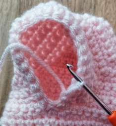 Inside of the cardigan armhole with the hook working the extra underarm stitches