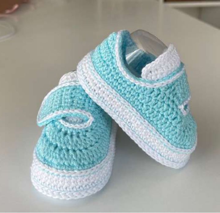 Pair of aqua crochet baby sneakers with white soles, white tongues and closed straps