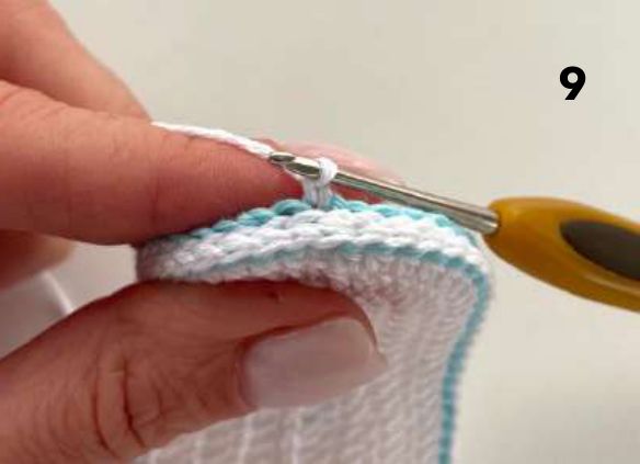 Crochet hook joining white yarn into the aqua slip stitch edge of the sole at the heel