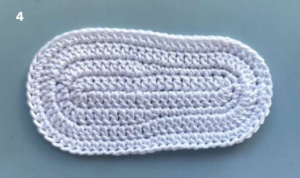 Finished oval white crochet sole after the half double crochet round