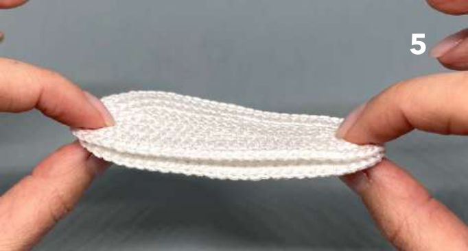Two white crochet soles held together with the wrong sides in