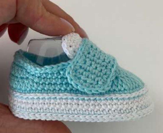Crochet sneaker with the aqua strap closed over the white tongue