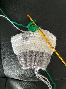 Green loop pulled through the first stitch to close the bobble