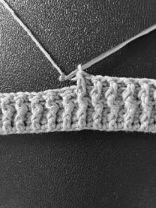 Gray crochet band with the hook going behind a stitch for a back post double crochet