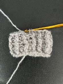 White yarn pulled through the last loops of the gray cuff