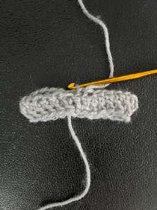Gray crochet band turned upside down with the hook in the bottom of the first stitch