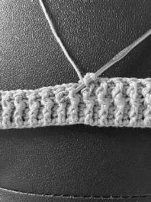 Gray crochet band with the hook going around the front of a stitch for a front post double crochet