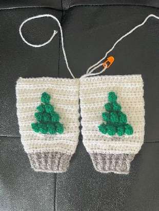 Two white crochet legs with green trees laid side by side, ready to join