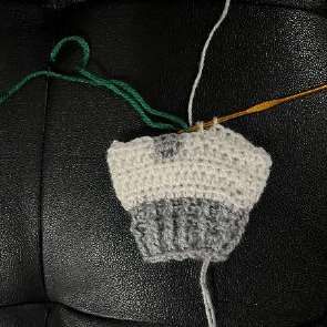 Green yarn joined above the trunk on the white crochet leg