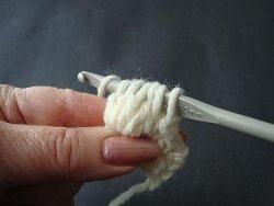 Hook holding the loops of five double crochet stitches for a popcorn