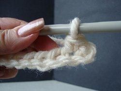 Hook working a double crochet next to a single crochet in a cream seed stitch row