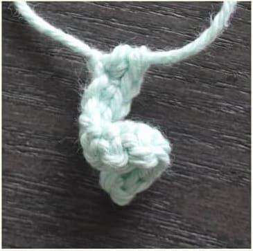 A mint green crochet tentacle curling into a spiral on its yarn tail