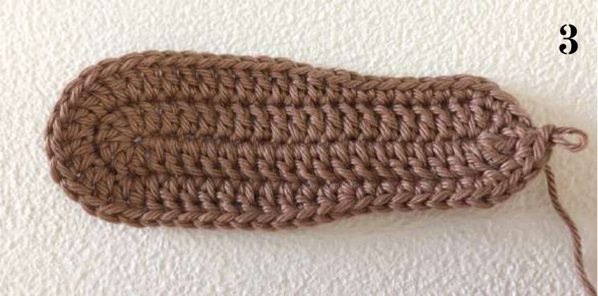 Brown crochet sole after round 2, long and rounded at both ends