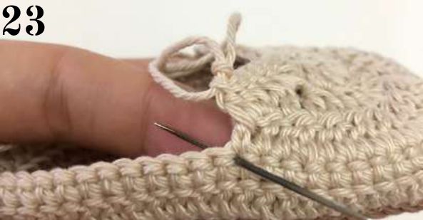 Tapestry needle pointing to the stitch for the last dc of row 1