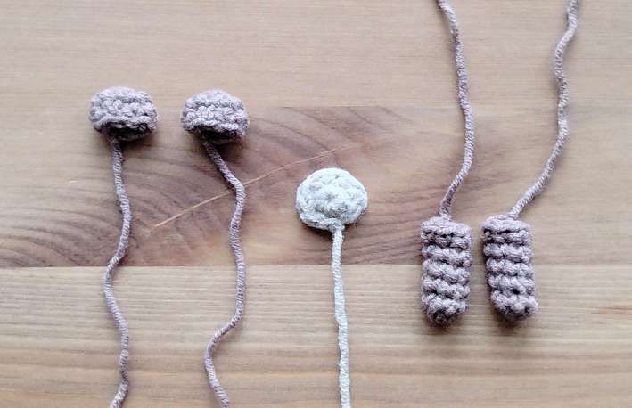Crochet bear pieces laid out with their tails: two ears, a cream muzzle and two arms
