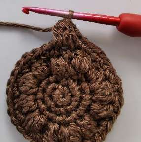 A finished bobble standing out from a brown crochet circle
