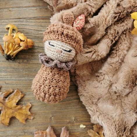 Pine cone baby doll in soft pink and lilac, with a ruffled collar and a cap with a stalk